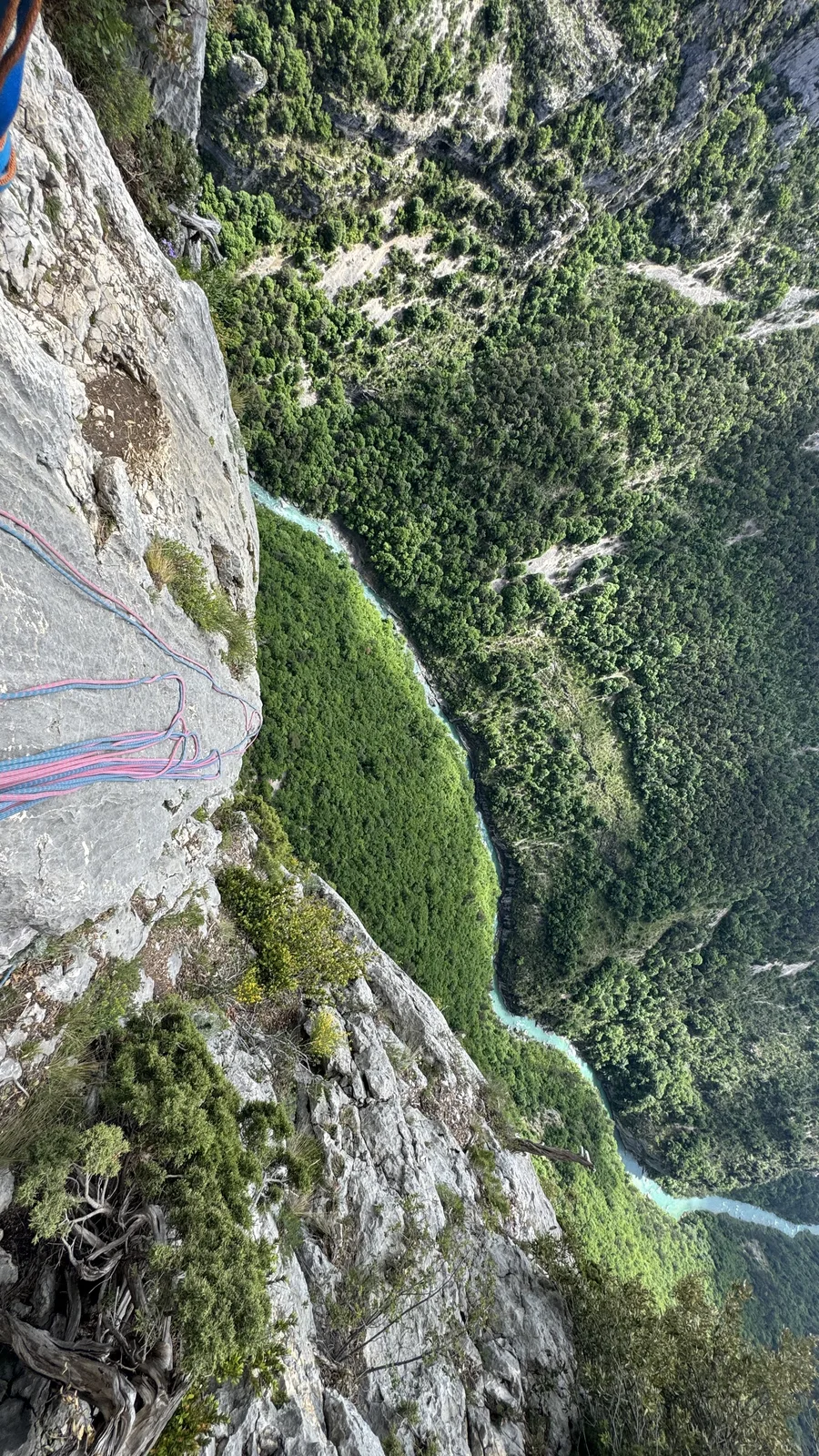 Vue plongeante depuis une paroi, deux brins de corde rouge et bleue qui s'éloignent vers la vallée