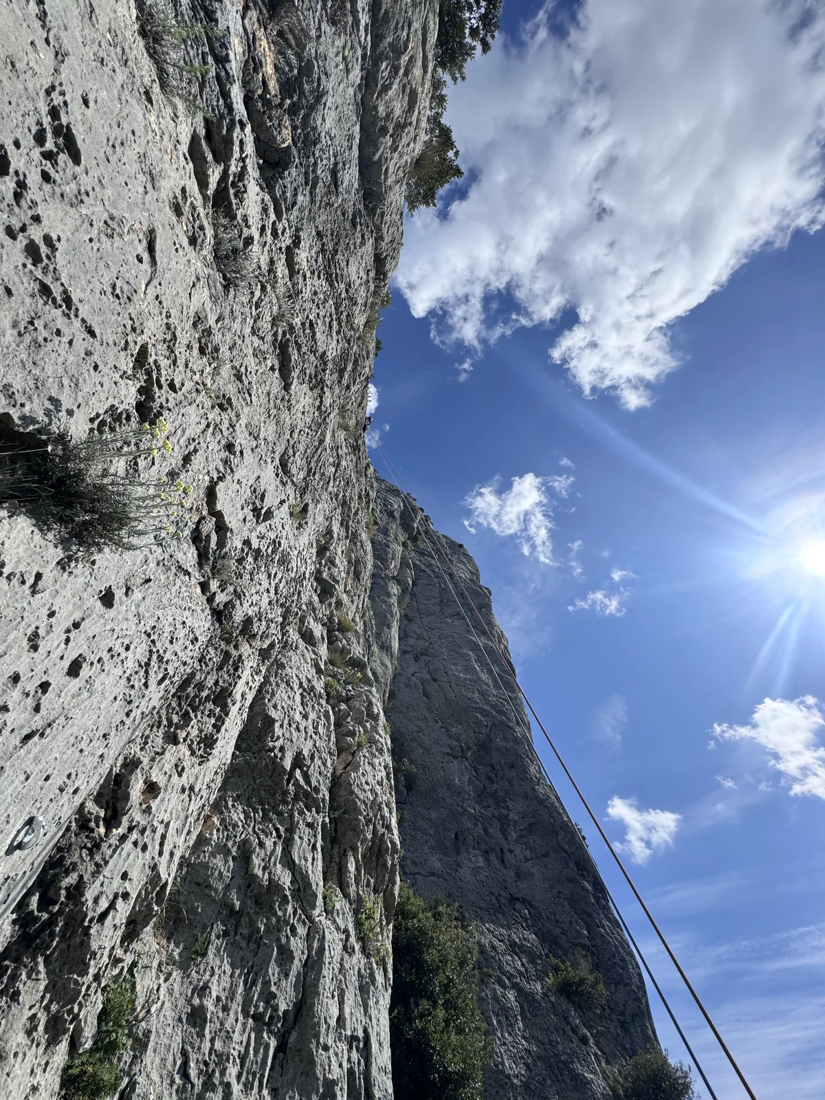Paroi calcaire en contre-plongée avec un soleil de contre-jour et un ciel bleu nuageux