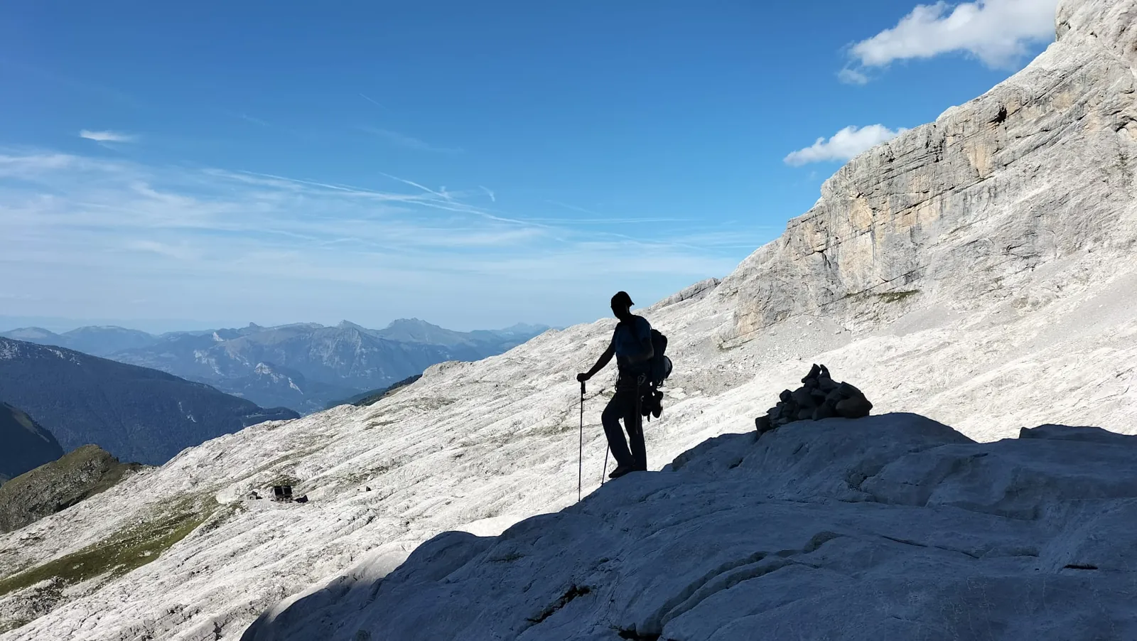 Silhouette d'un grimpeur sur une dalle calcaire, chaîne de montagnes au loin