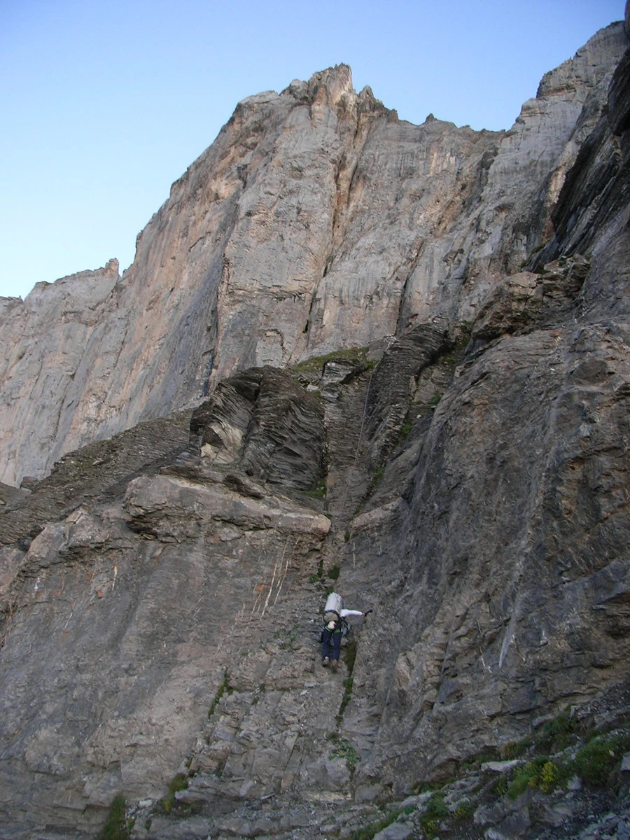 Massif calcaire alpin en lumière matinale, prairie verte en contrebas
