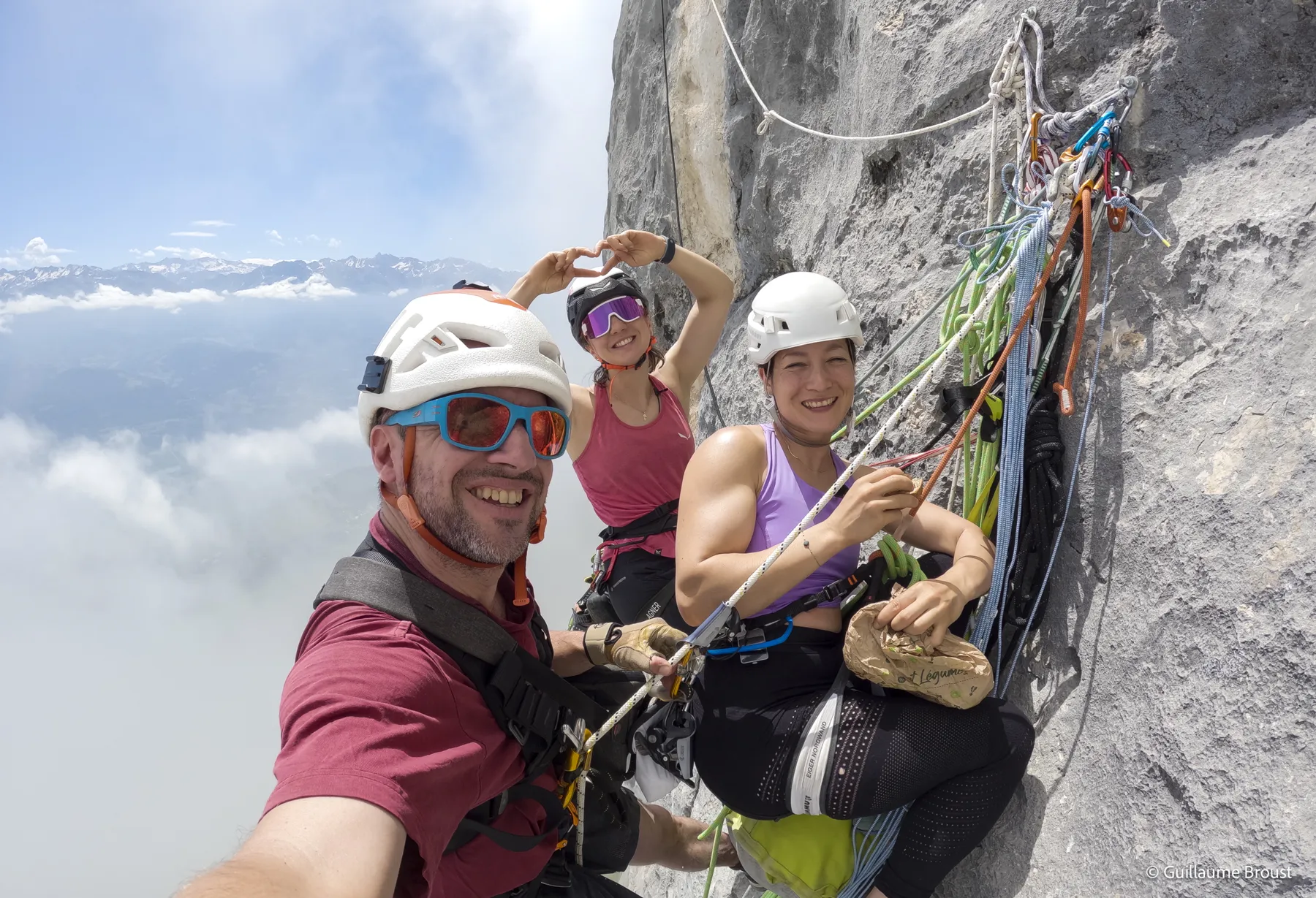Le réalisateur et les deux grimpeuses réunis au relais, mer de nuages en arrière-plan