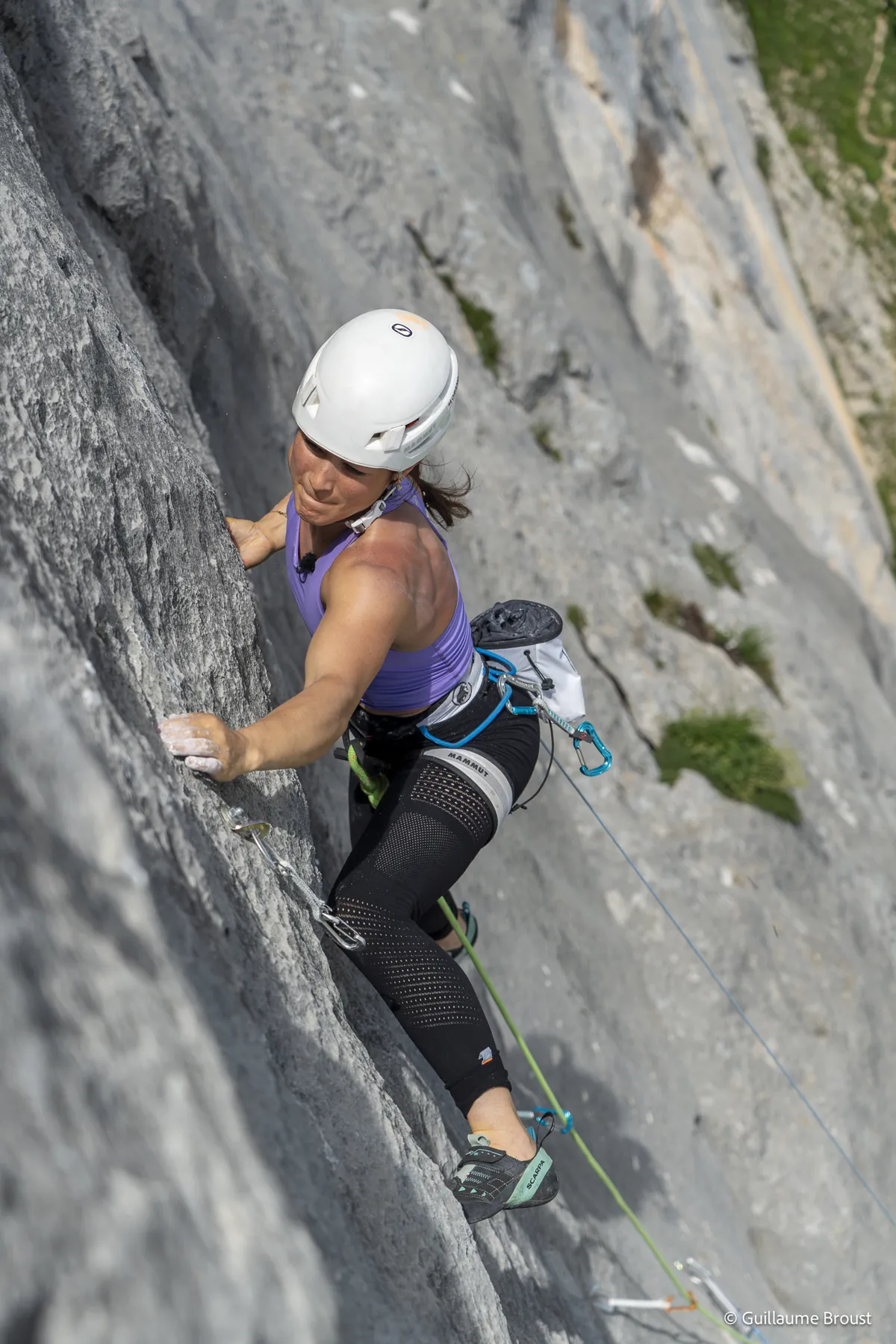 Grimpeuse concentrée sur une dalle grise, vue de haut