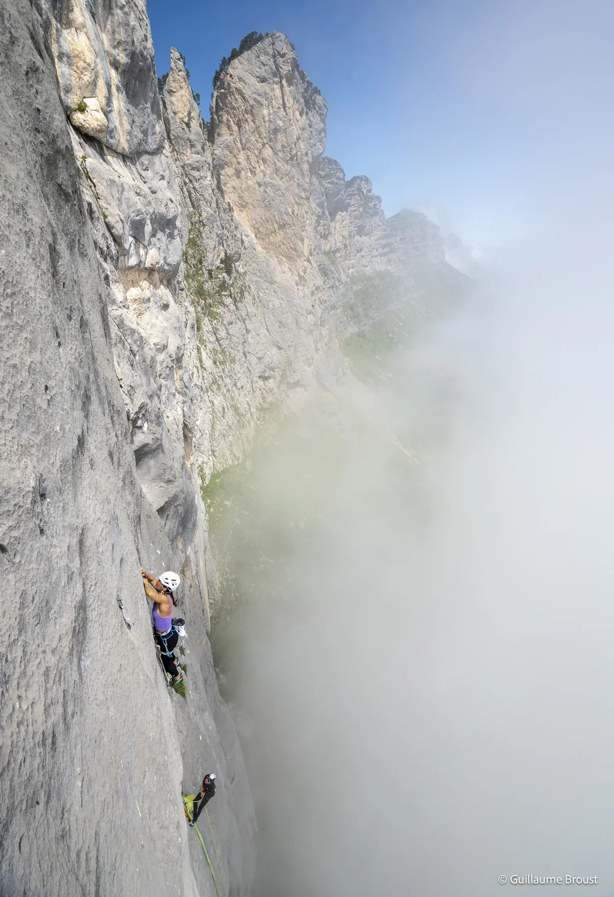 Cordée minuscule sur un grand mur vertical, aiguilles rocheuses et brume