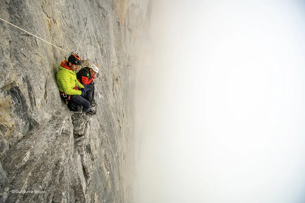 Deux grimpeurs blottis au relais dans le brouillard, face nord de l'Eiger